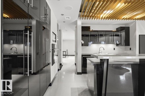 Contemporary kitchen featuring a high-gloss black cabinetry, integrated appliances, and a unique slatted wood ceiling detail - 8709 92A Avenue, Edmonton, AB - Indoor Photo Showing Kitchen With Upgraded Kitchen