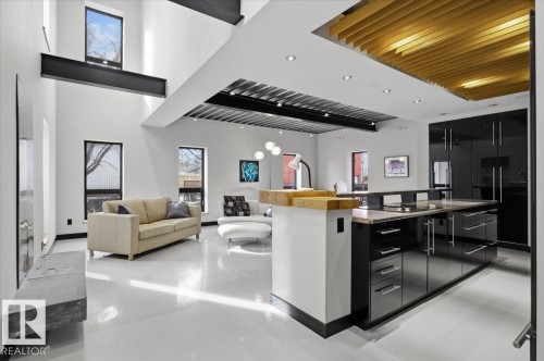 Open concept living area featuring high ceilings, exposed structural beams, and large windows - 8709 92A Avenue, Edmonton, AB - Indoor