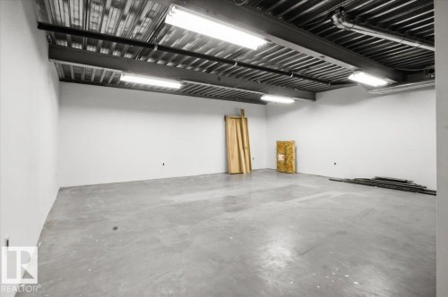 Spacious interior featuring a concrete floor, white walls, and an exposed industrial ceiling with fluorescent lighting - 8709 92A Avenue, Edmonton, AB - Indoor Photo Showing Garage