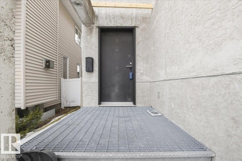 Industrial-style metal grate landing with a solid dark entry door - 8709 92A Avenue, Edmonton, AB - Outdoor With Exterior