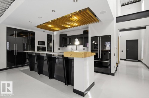 Contemporary kitchen featuring high-gloss black cabinetry, integrated appliances, and a prominent island with a light wood-finish countertop accent - 8709 92A Avenue, Edmonton, AB - Indoor Photo Showing Kitchen