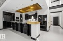 Contemporary kitchen featuring high-gloss black cabinetry, integrated appliances, and a prominent island with a light wood-finish countertop accent - 8709 92A Avenue, Edmonton, AB  - Indoor Photo Showing Kitchen 