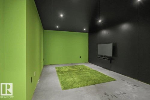Room featuring a vibrant green accent wall, matte black ceiling, recessed lighting, and an integrated wall-mounted media console - 8709 92A Avenue, Edmonton, AB - Indoor Photo Showing Other Room