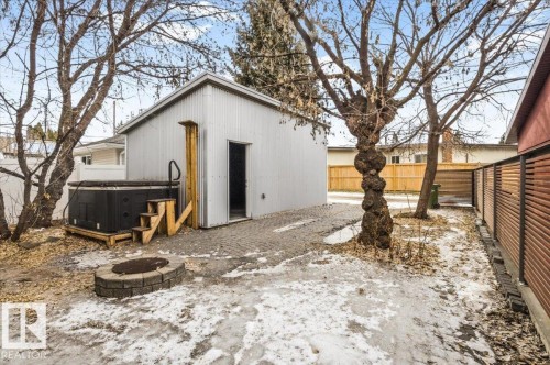 Rear yard featuring a detached outbuilding, paver patio, built-in fire pit, and privacy fencing - 8709 92A Avenue, Edmonton, AB - Outdoor