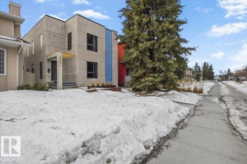 Modern facade featuring multiple large windows, a contrasting blue vertical accent panel, a prominent front entrance with an extended overhang, and a built-in planter box - 8709 92A Avenue, Edmonton, AB - Outdoor