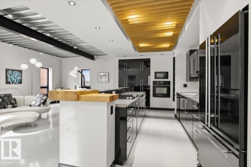 Open-concept living space featuring a modern kitchen with black high-gloss cabinetry, integrated appliances, and a stainless steel refrigerator - 8709 92A Avenue, Edmonton, AB - Indoor Photo Showing Kitchen