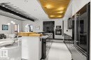 Open-concept living space featuring a modern kitchen with black high-gloss cabinetry, integrated appliances, and a stainless steel refrigerator - 8709 92A Avenue, Edmonton, AB  - Indoor Photo Showing Kitchen 