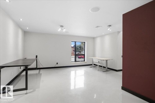 Spacious room featuring light-toned flooring and walls, with a contrasting dark accent wall - 8709 92A Avenue, Edmonton, AB - Indoor Photo Showing Other Room