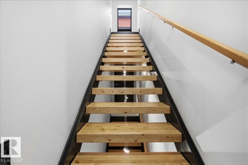 Contemporary staircase featuring wood treads, a dark metal stringer, and a natural wood handrail - 8709 92A Avenue, Edmonton, AB - Indoor Photo Showing Other Room