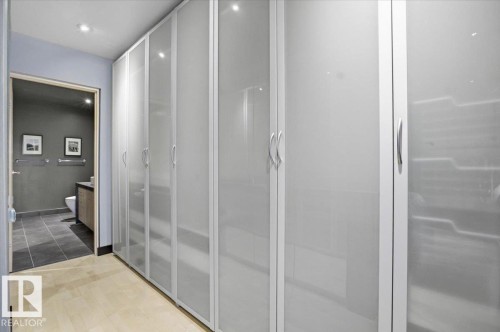 Integrated storage solution featuring multiple frosted glass wardrobe doors with brushed metal handles - 8709 92A Avenue, Edmonton, AB - Indoor Photo Showing Bathroom