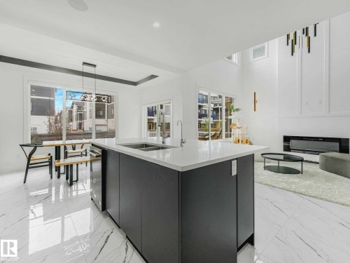 Open-concept living space with a central kitchen island featuring a stainless steel sink and modern cabinetry - 16307 19 Avenue, Edmonton, AB - Indoor Photo Showing Kitchen With Double Sink