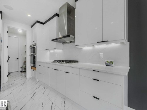 Modern kitchen featuring high-gloss white cabinetry with dark hardware - 16307 19 Avenue, Edmonton, AB - Indoor Photo Showing Kitchen