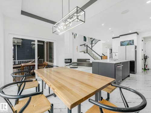 Dining area featuring a live-edge wood table, modern linear chandelier, and wide plank flooring - 16307 19 Avenue, Edmonton, AB - Indoor