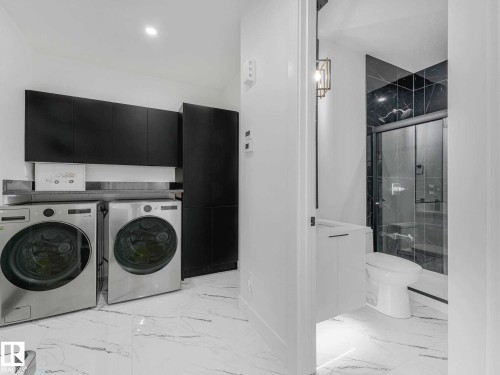 Laundry area featuring side-by-side appliances, dark cabinetry, and white marble-look flooring - 16307 19 Avenue, Edmonton, AB - Indoor Photo Showing Laundry Room