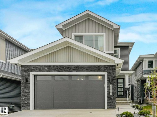 Modern exterior featuring stacked stone accents, horizontal siding, an attached garage, a contemporary front entry door, and a concrete driveway - 16307 19 Avenue, Edmonton, AB - Outdoor