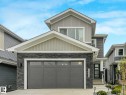 Modern exterior featuring stacked stone accents, horizontal siding, an attached garage, a contemporary front entry door, and a concrete driveway - 16307 19 Avenue, Edmonton, AB  - Outdoor 