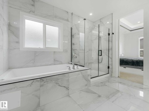 Sleek bathroom featuring a built-in soaking tub, a frameless glass shower enclosure, large format white tile flooring, and matching tiled walls - 16307 19 Avenue, Edmonton, AB - Indoor Photo Showing Bathroom