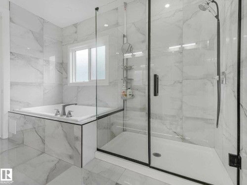 Spacious bathroom featuring a glass-enclosed shower, built-in soaking tub with deck-mounted fixtures, and large-format porcelain tile walls and flooring - 16307 19 Avenue, Edmonton, AB - Indoor Photo Showing Bathroom