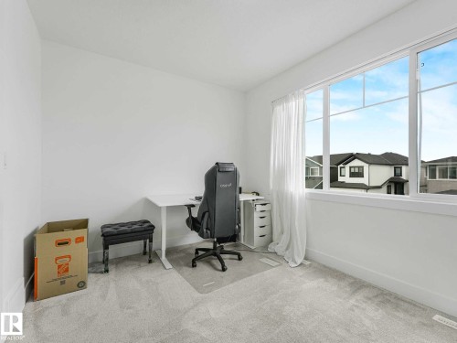 Bright interior space featuring a large multi-pane window, light gray carpeting, and white wall finishes - 16307 19 Avenue, Edmonton, AB - Indoor