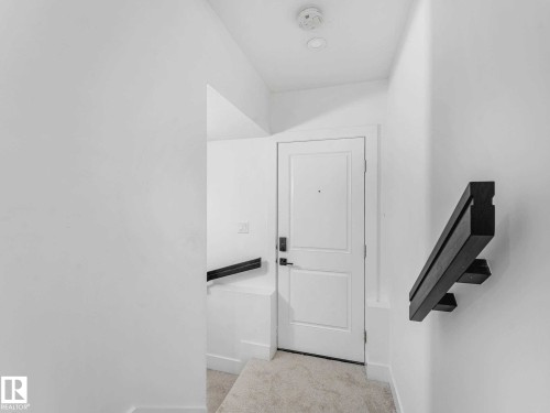 Entryway featuring a solid panel door, contemporary wall-mounted handrail, and soft carpeting - 16307 19 Avenue, Edmonton, AB - Indoor Photo Showing Other Room