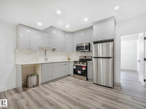 Modern kitchen featuring light gray cabinetry, stainless steel appliances, a white countertop, and a coordinating white tile backsplash - 16307 19 Avenue, Edmonton, AB - Indoor Photo Showing Kitchen With Upgraded Kitchen