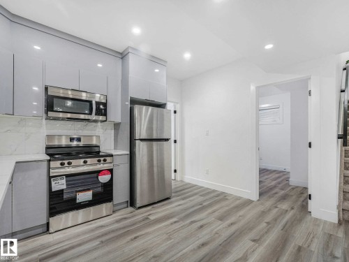 Kitchen featuring light gray cabinetry, stainless steel appliances, white countertops, and a white tile backsplash - 16307 19 Avenue, Edmonton, AB - Indoor Photo Showing Kitchen