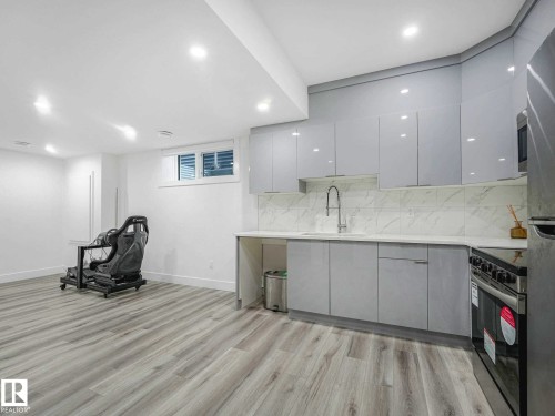 Modern kitchen space featuring gray cabinetry, light countertops, and a white tile backsplash - 16307 19 Avenue, Edmonton, AB - Indoor
