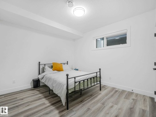 Bright room featuring wood-finish flooring, white baseboards, and a single window with blinds - 16307 19 Avenue, Edmonton, AB - Indoor Photo Showing Bedroom