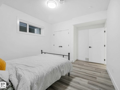 Bright room featuring light wood-finish flooring, a window with horizontal blinds, and white walls - 16307 19 Avenue, Edmonton, AB - Indoor Photo Showing Bedroom