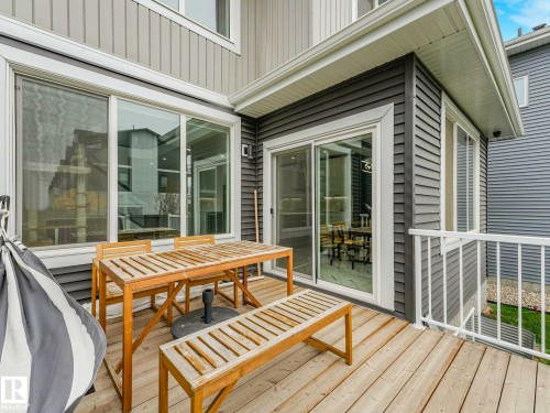 Upper-level wood-finish deck with white railing, featuring sliding glass doors and large windows - 16307 19 Avenue, Edmonton, AB - Outdoor With Deck Patio Veranda With Exterior