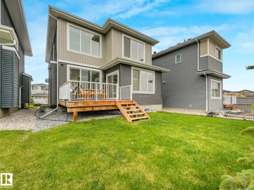 Rear exterior featuring a wood deck with white railings and stairs descending to a green lawn - 16307 19 Avenue, Edmonton, AB - Outdoor With Deck Patio Veranda