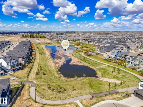Aerial perspective showcasing a residential community centered around a natural pond - 16307 19 Avenue, Edmonton, AB - Outdoor With View