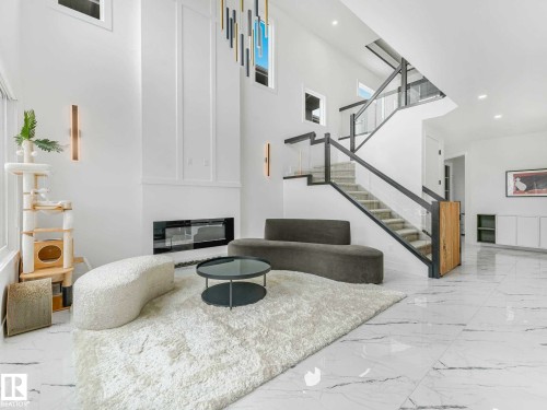 Grand foyer with soaring ceilings and a contemporary glass-paneled staircase - 16307 19 Avenue, Edmonton, AB - Indoor Photo Showing Other Room With Fireplace