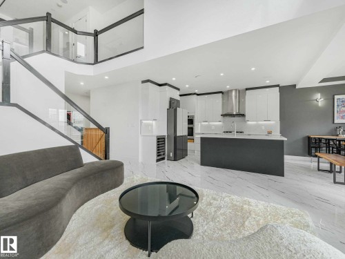 Open-concept living space featuring a modern kitchen with a large island, stainless steel appliances, and white cabinetry - 16307 19 Avenue, Edmonton, AB - Indoor