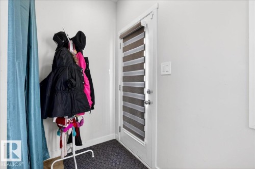 White interior door with integrated horizontal blinds and polished hardware, set against light-toned walls and dark patterned flooring - 5315 22 Avenue, Edmonton, AB - Indoor Photo Showing Other Room