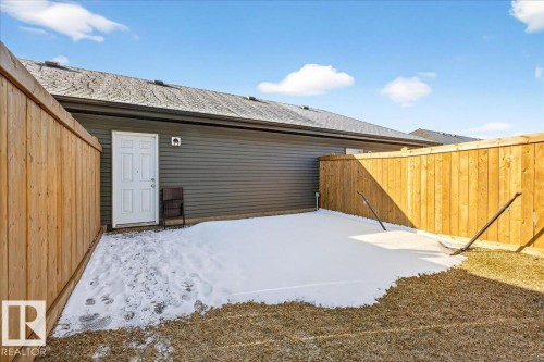 Fenced backyard featuring a concrete patio, wood fencing, and a white exterior door - 5315 22 Avenue, Edmonton, AB - Outdoor With Exterior