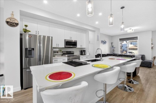 Modern kitchen featuring a large island with seating, stainless steel appliances, white cabinetry, and recessed lighting - 5315 22 Avenue, Edmonton, AB - Indoor