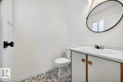 Bathroom featuring a white vanity with a laminate countertop, an oval-framed mirror, and a ceramic toilet - 32 1820 56 Street, Edmonton, AB - Indoor Photo Showing Bathroom