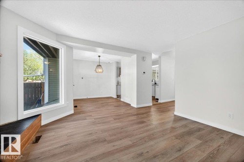 Spacious room featuring wood-finish flooring, a large bay window, and white trim - 32 1820 56 Street, Edmonton, AB - Indoor Photo Showing Other Room
