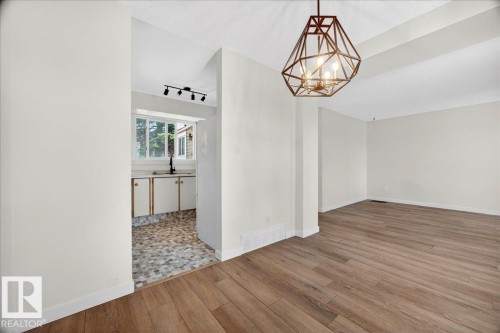 Spacious interior featuring wood-finish flooring, a geometric pendant light fixture, and a neutral color palette - 32 1820 56 Street, Edmonton, AB - Indoor Photo Showing Other Room