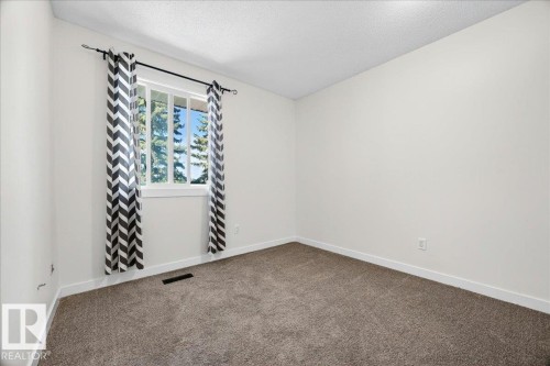 Carpeted room featuring a white-framed window, white walls, white baseboards, and a textured ceiling - 32 1820 56 Street, Edmonton, AB - Indoor Photo Showing Other Room