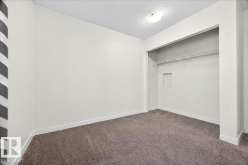 Neutral-toned carpeting, white baseboards, and a dedicated closet space with wire shelving - 32 1820 56 Street, Edmonton, AB - Indoor Photo Showing Other Room