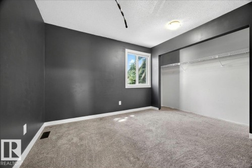 Carpeted room with a window, dark gray walls, white trim, and a built-in closet with wire shelving - 32 1820 56 Street, Edmonton, AB - Indoor Photo Showing Other Room