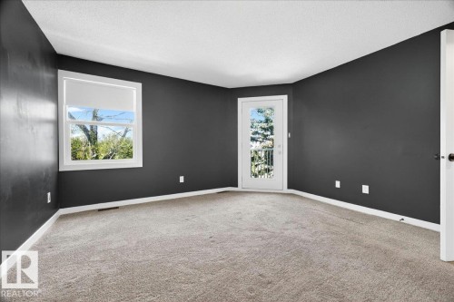 Carpeted room featuring dark walls, white trim, and a textured ceiling - 32 1820 56 Street, Edmonton, AB - Indoor Photo Showing Other Room