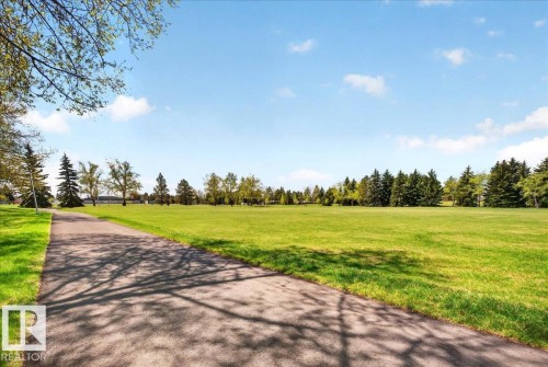 Paved pathway bordered by manicured green space, mature evergreen trees, and deciduous trees - 32 1820 56 Street, Edmonton, AB - Outdoor With View