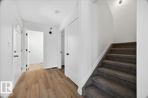 Entryway featuring wood-finish flooring, white trim, and a carpeted staircase - 32 1820 56 Street, Edmonton, AB - Indoor Photo Showing Other Room