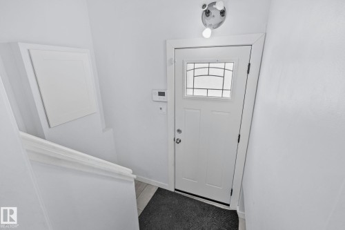 White entrance door with an arched decorative glass insert and two lower panels - 12002 37 Street, Edmonton, AB 