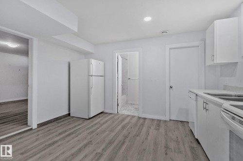 Open-concept kitchen area featuring wood-finish flooring and white cabinetry - 12002 37 Street, Edmonton, AB 