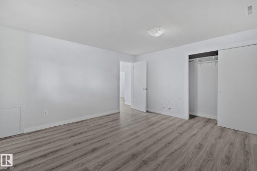 Spacious room featuring wood-finish flooring, white baseboards, and a neutral wall palette - 12002 37 Street, Edmonton, AB 