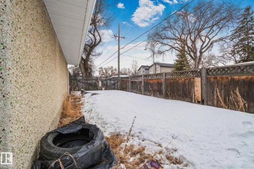 Side yard with a textured aggregate exterior wall, white soffit, and a wooden lattice fence - 12002 37 Street, Edmonton, AB 